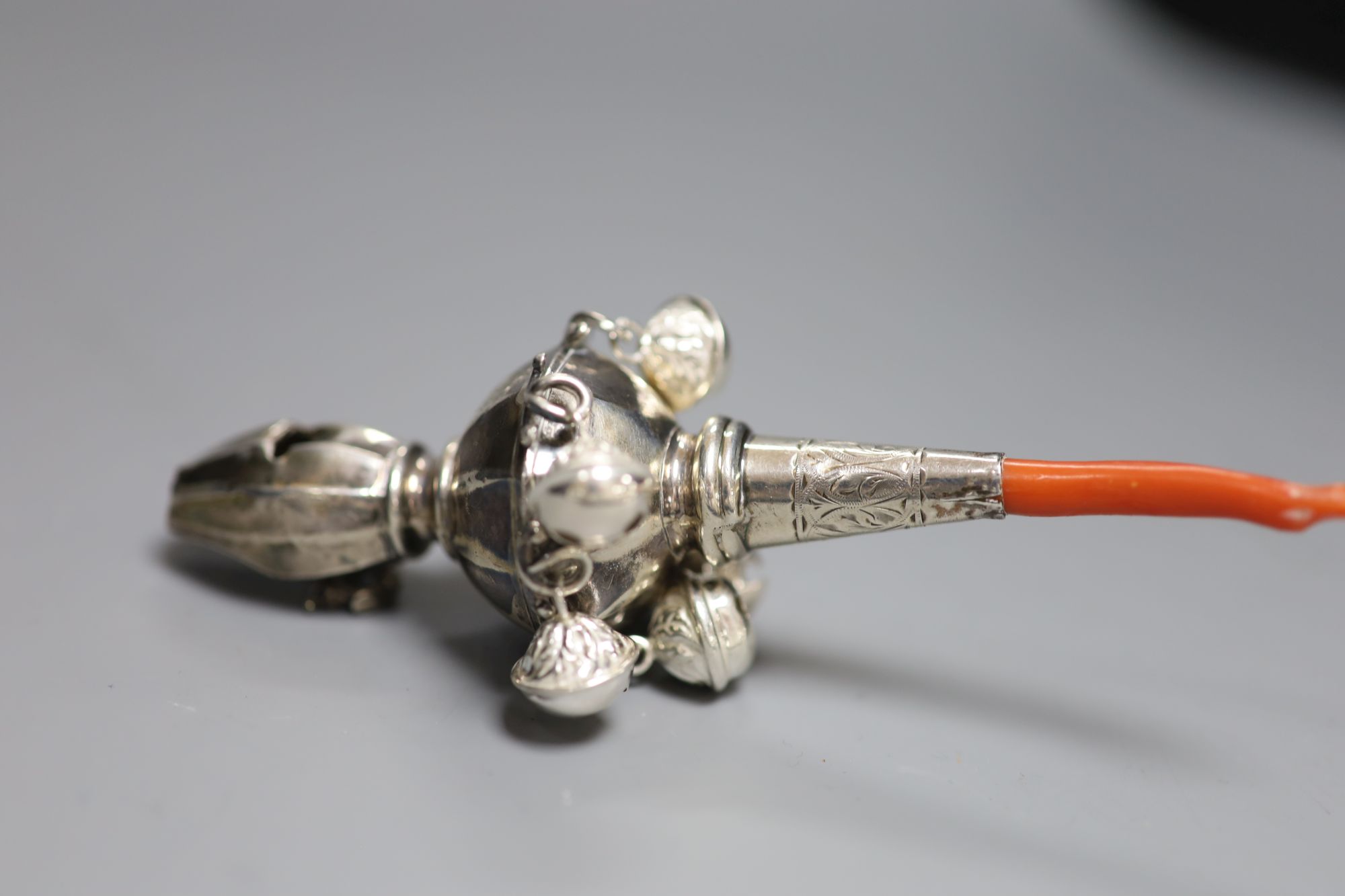 A George V silver childs rattle with coral teether and six bells, Crisford & Norris, Birmingham, 1911, 13cm.